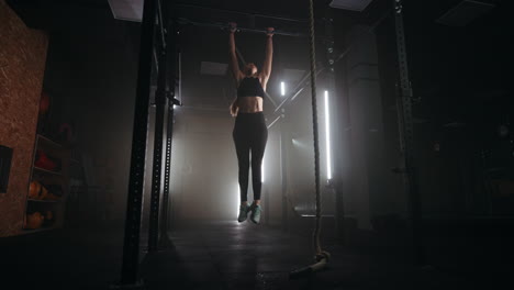 young-slender-woman-is-doing-sport-in-gym-jumping-on-crossbar-and-lifting-her-legs-up